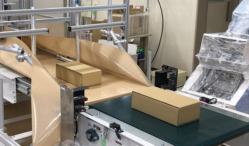 商品を投入し、自動で紙製宅配袋を成形・包装する工程の様子。