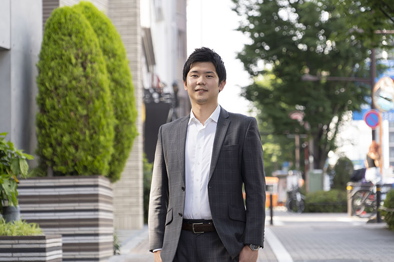 街中でスーツを着用し立っているザ・パックの担当営業